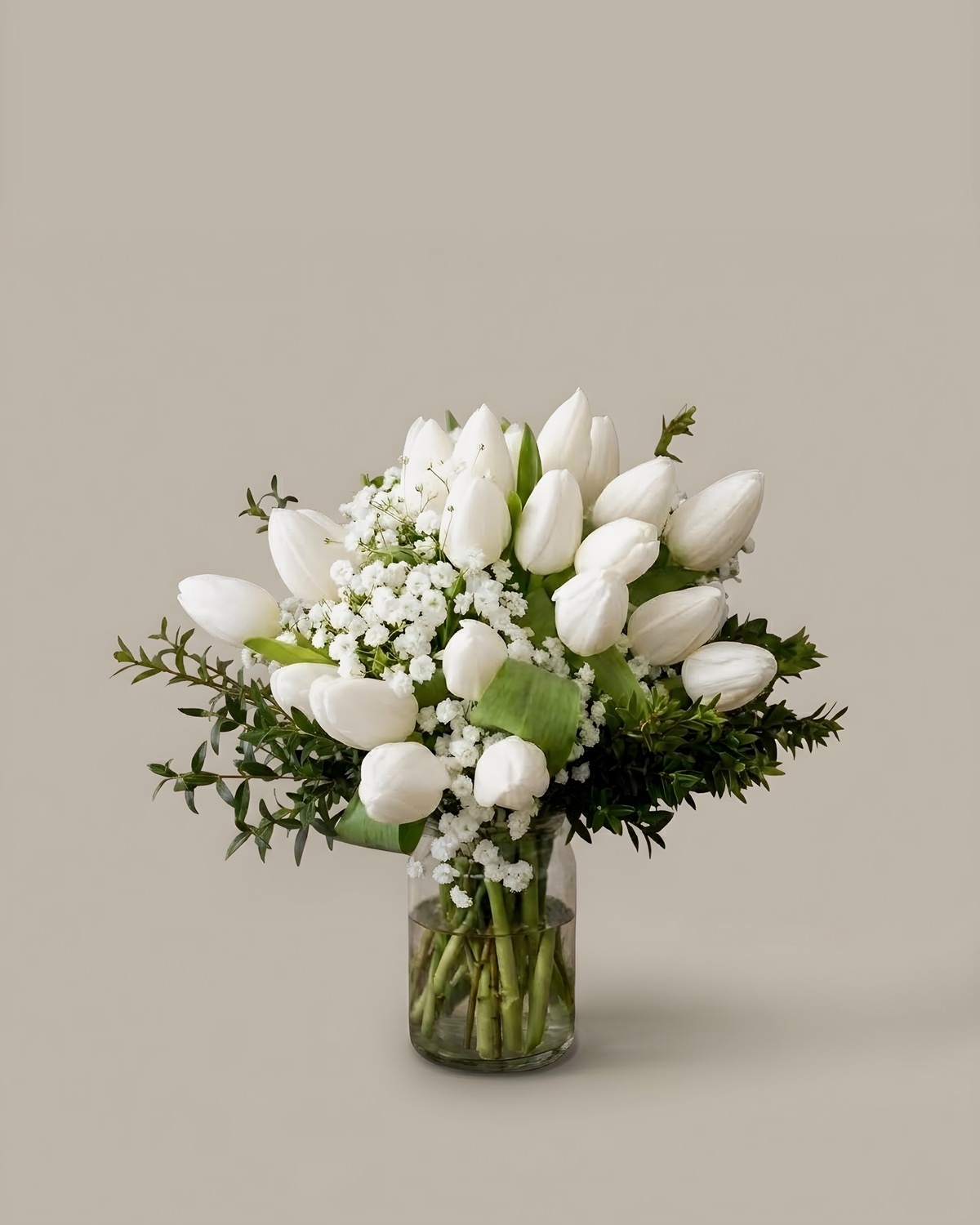 White tulips and baby's breath in a clear glass vase