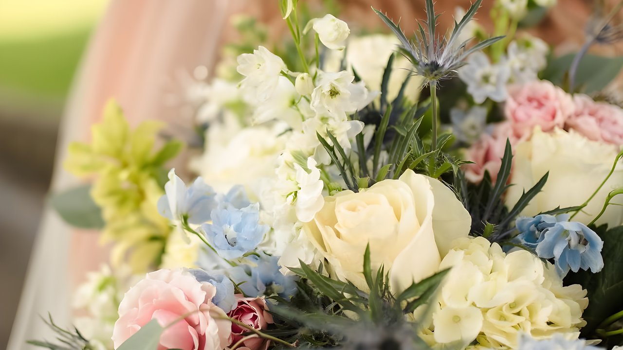 A bridal bouquet built by Greenville Floral, with cream roses, blue delphinium, pink carnations, white stock and sea holly.