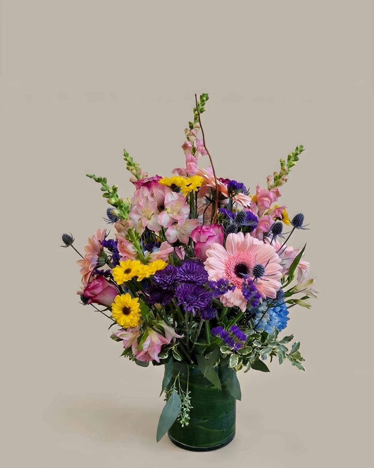 Pink and purple garden arrangement with yellow daisies and a striped ribbon