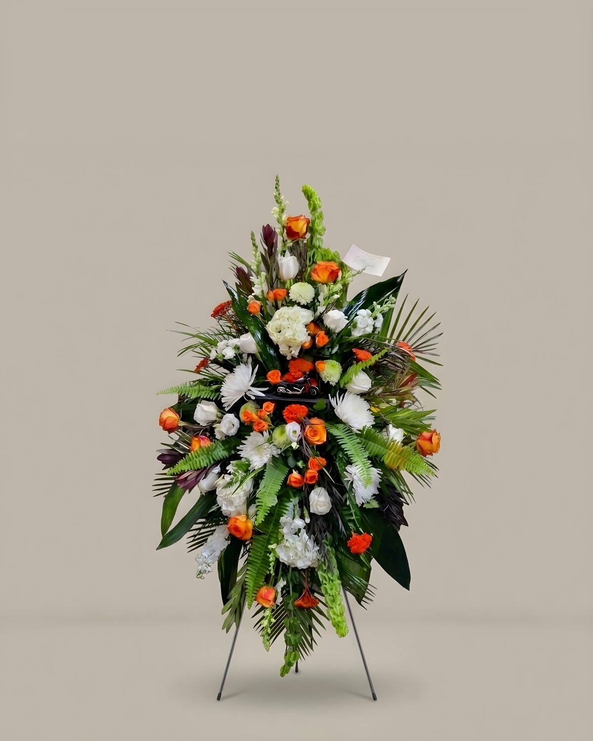 White and orange standing funeral spray on an easel