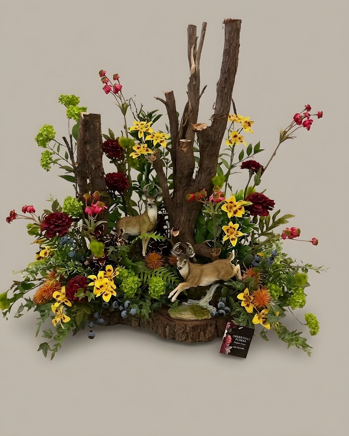 Silk woodland scene with birch posts, dried stems and deer figures on a log slice