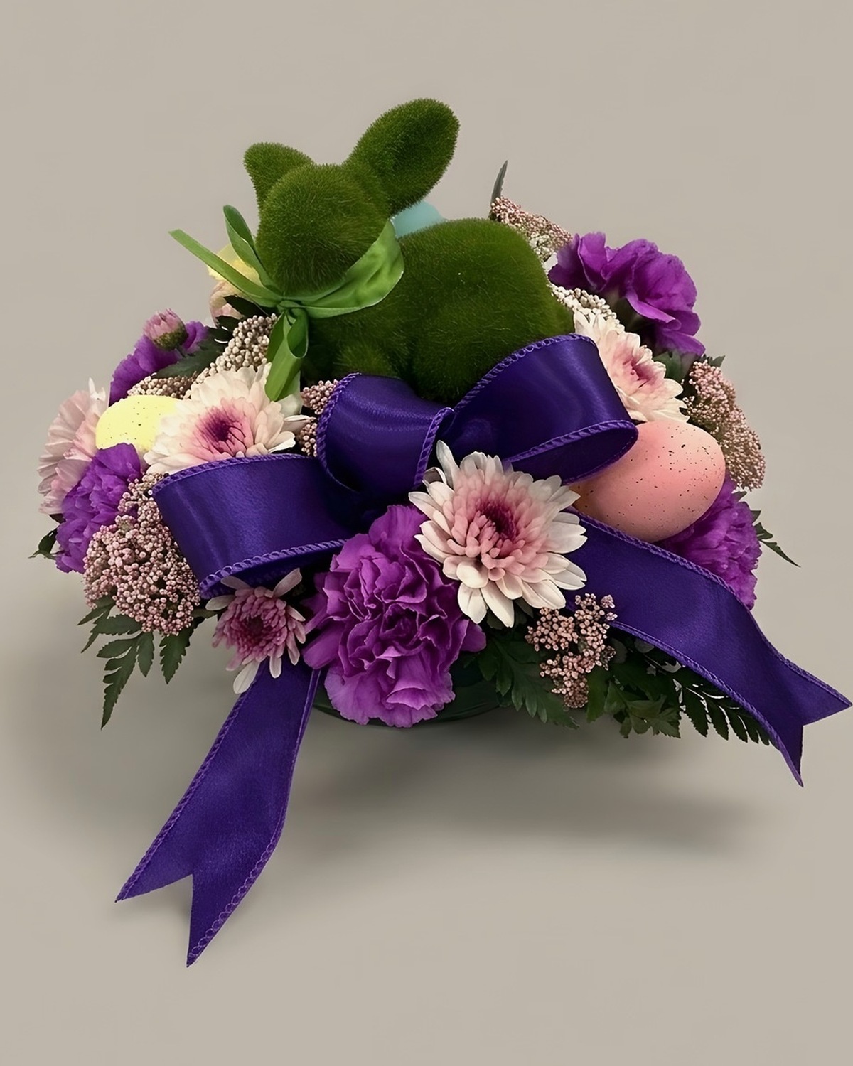Pastel daisies and carnations with decorated eggs and a purple bow