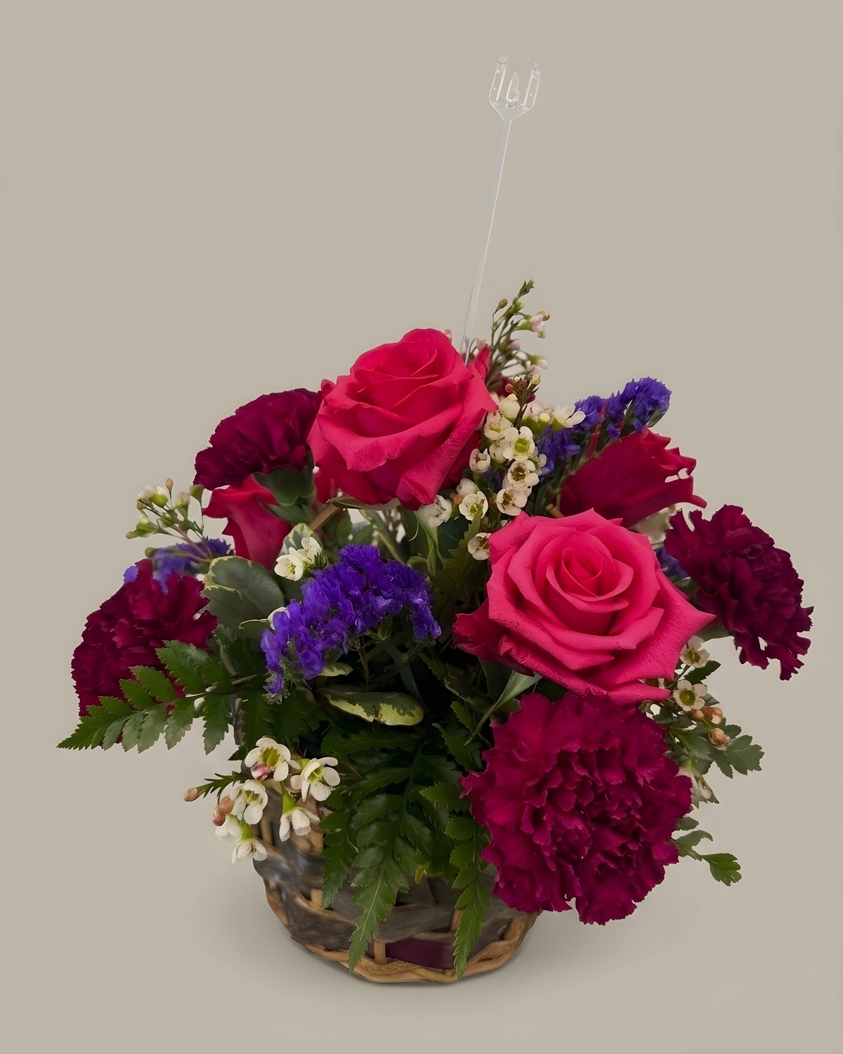 Magenta roses, purple carnations and burgundy blooms in a glass vase