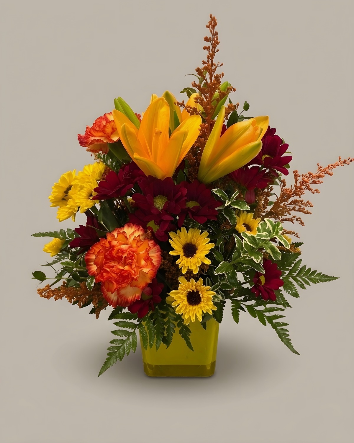 Orange lilies, sunflowers and red carnations in a gold cube vase